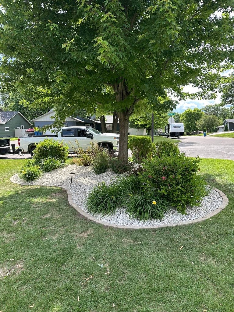 Symmetric white rock foundation landscape bed with flowering shrubs along the front of a home